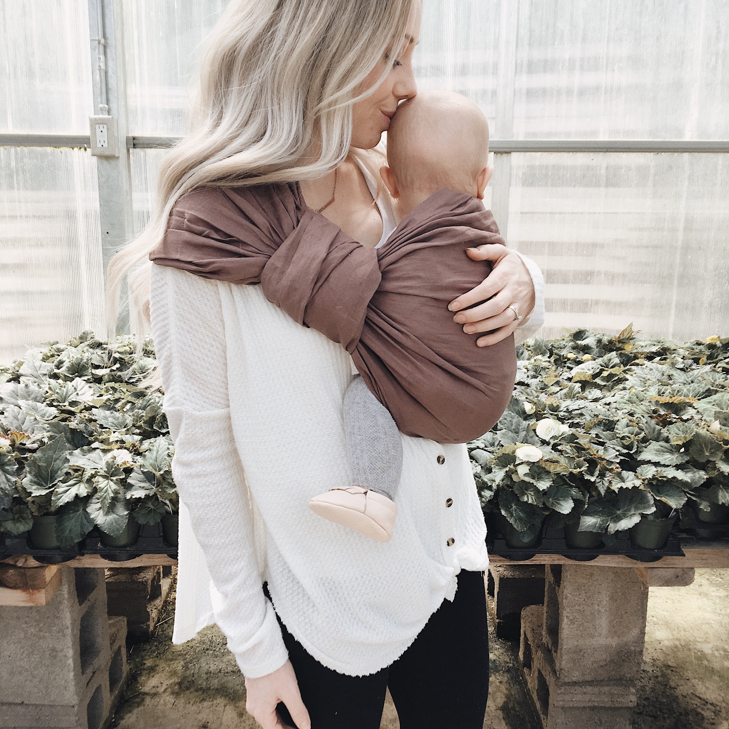 A mother holding her baby in a sling made by a Canadian business